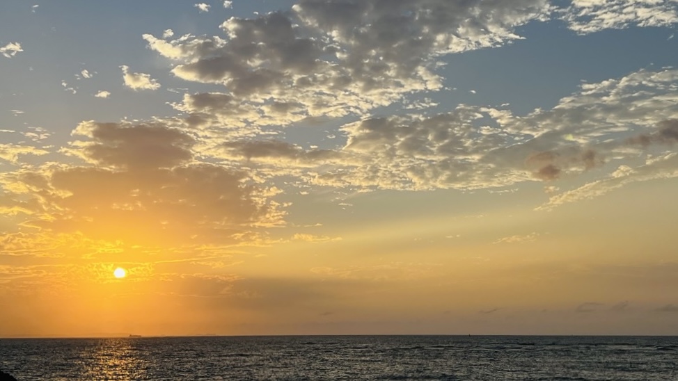 日差しが和らぎ、空が青からオレンジへとドラマチックに変化する夕暮れ時の沖縄の海