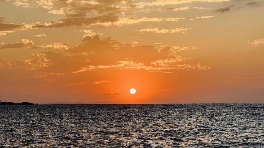 海に沈む直前の夕日。空と海が美しいオレンジ色に染まる沖縄西海岸のサンセット。
