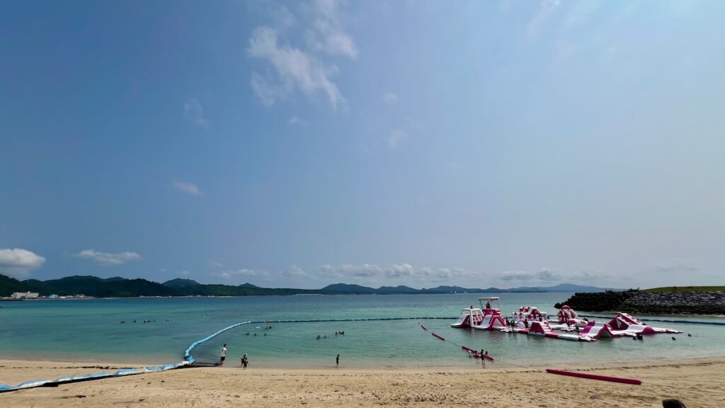 店舗横の階段からビーチを見下ろす風景。水遊びを楽しむ人々の姿。