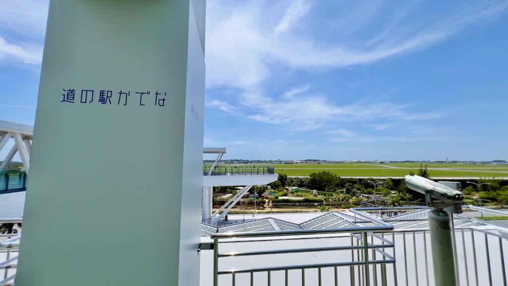 柱に書かれた道の駅かでなの文字と、背景に広がる嘉手納基地の滑走路