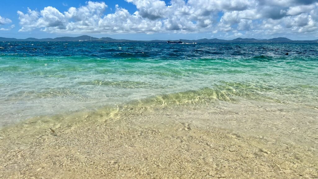 青空の下に、広がる大泊ビーチの透明度が高いエメラルドグリーンの海