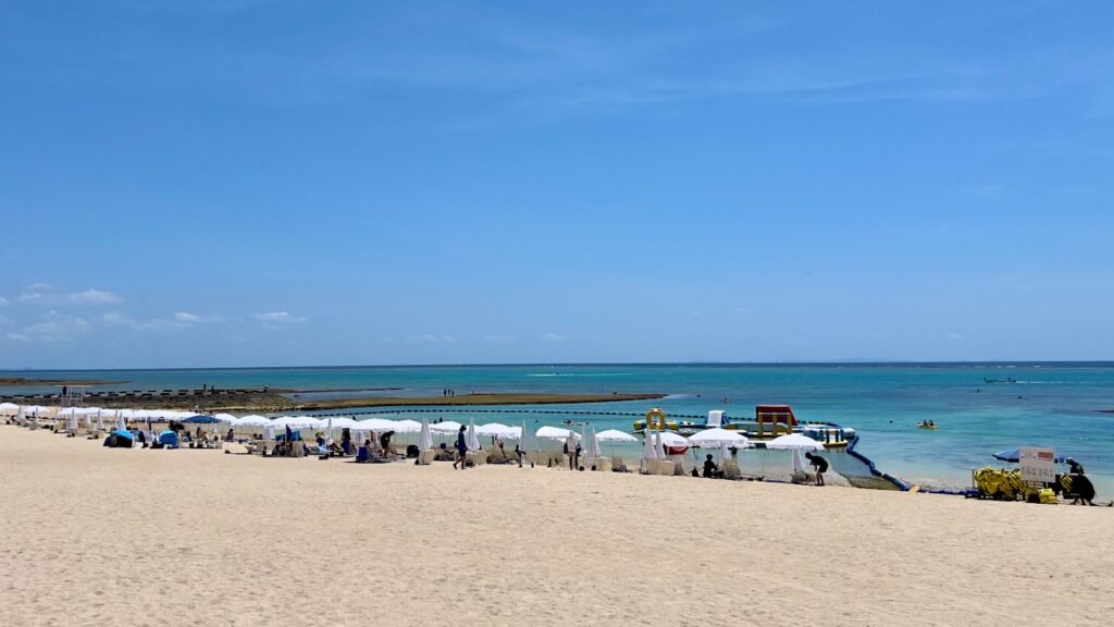 綺麗な白い砂浜の上に、白いパラソルが並ぶ残波ビーチの風景