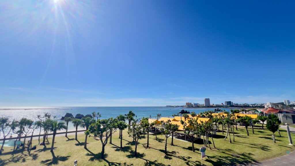 高い位置からみた空と海と木々と黄色いテントが広がるアラハビーチの風景