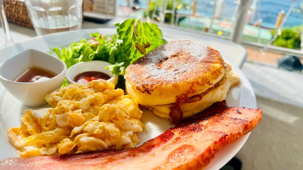 ベーコンとスクランブルエッグ、サラダが付いている美味しそうなハノンのパンケーキの画像