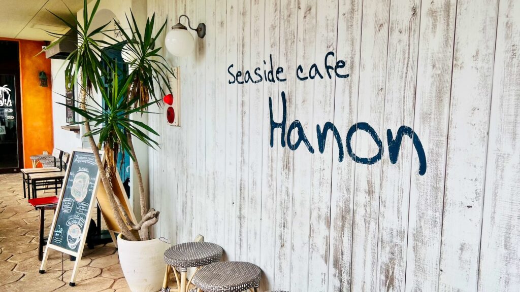 白い木製壁にSeaside Cafe Hanonの文字が書かれたハノンの入り口