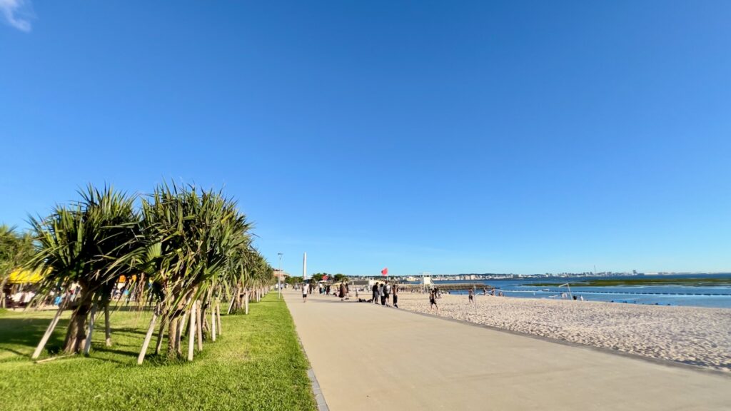 左には芝生と南国の木々が並び、右には白い砂浜と海が広がるアラハビーチに向かう遊歩道
