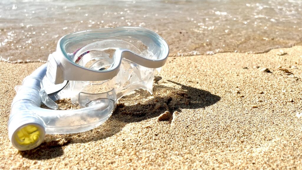 白砂のビーチの波打ち際にシュノーケルマスクが置いてある画像