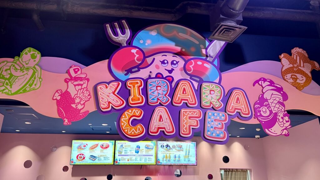 カラフルな文字で「KIRARA CAFE」と書かれた立体的な看板や、可愛らしいキャラクターのイラストが装飾されたカフェの看板とメニューモニター